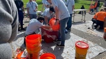 Students pouring a mixture into a large red box