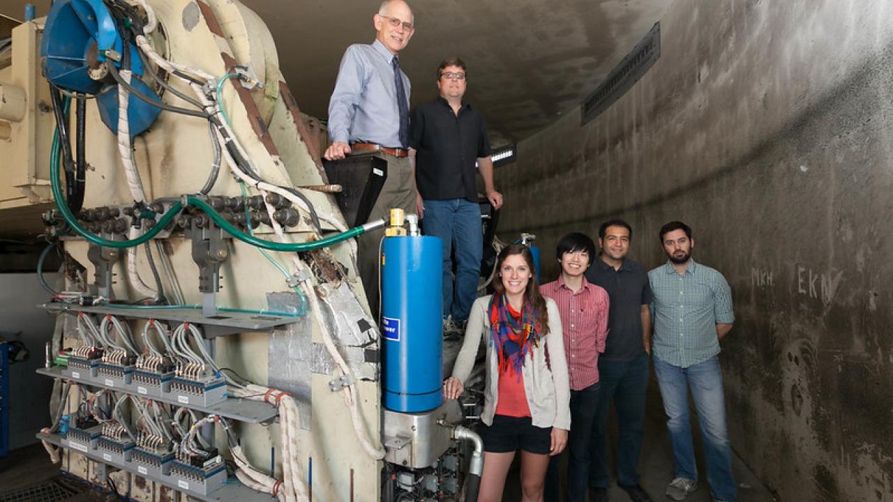 Group of students and faculty standing next to equipment 