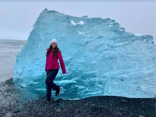 A student leans against a large ice block