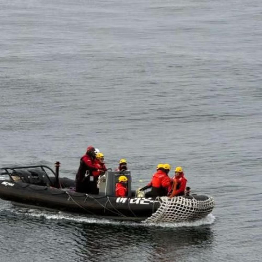 Rescue team in red jackets on a boat navigating calm waters.
