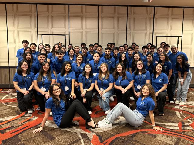 large group of students, all wearing blue polos, pose for a group photo