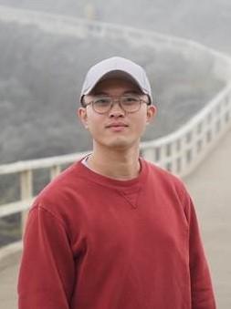 Graduate Student Ivan Xiao standing on a bridge wearing a red sweater and a white baseball cap