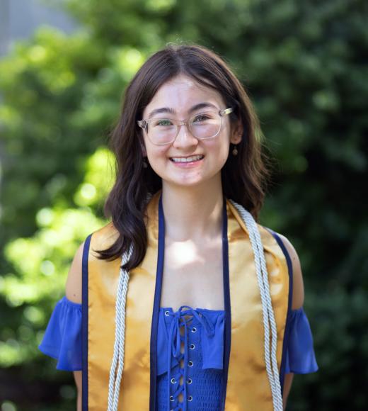 A woman wearing a UC Davis stole smiles