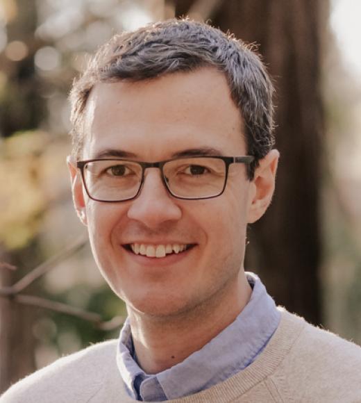 Brown haired man with glasses is smiling at the camera
