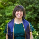A woman wearing a UC Davis stole smiles 