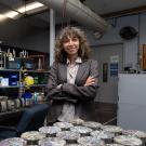 Somayeh Nassiri with arms crossed standing behind trays of pavement samples in a lab.